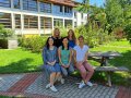 Fünf Frauen sitzen auf einer Bank im Garten